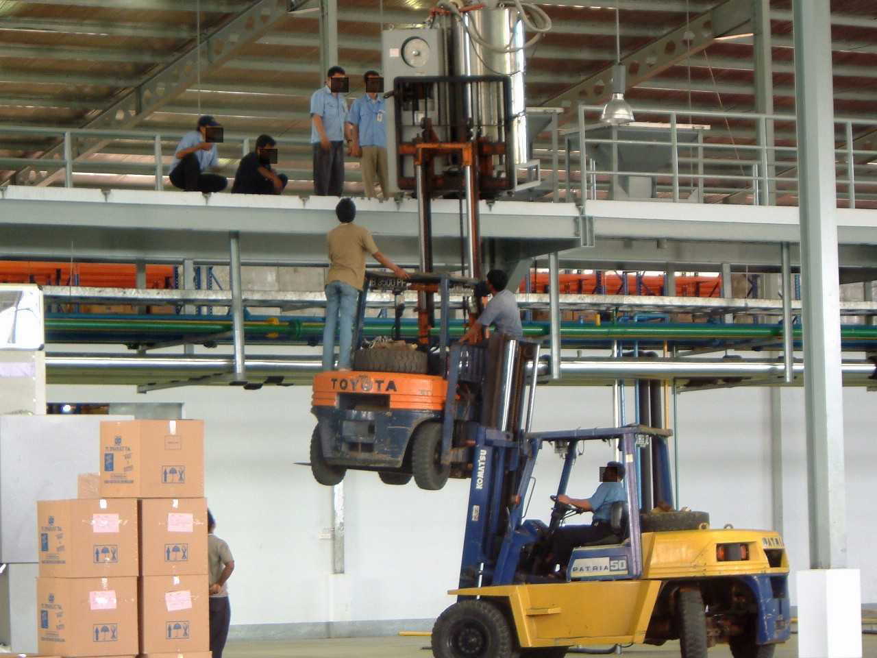 A forklift picking up another forklift which has lifted some equipment